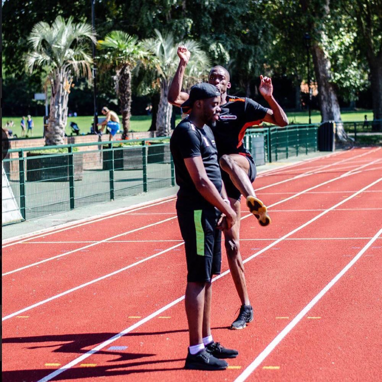 Personal trainer Hisham jumping over a client on an athletics track in London
